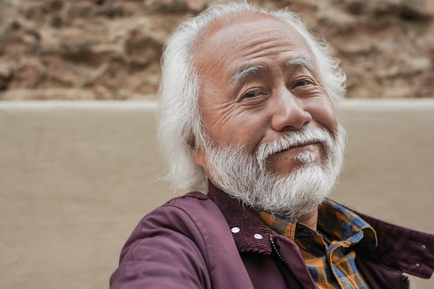 Happy senior asian man smiling on camera Elderly person taking a selfie