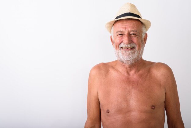 happy senior bearded man smiling while wearing hat shirtless on white