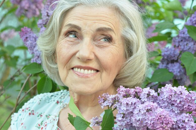 Happy senior beautiful woman with lilacs