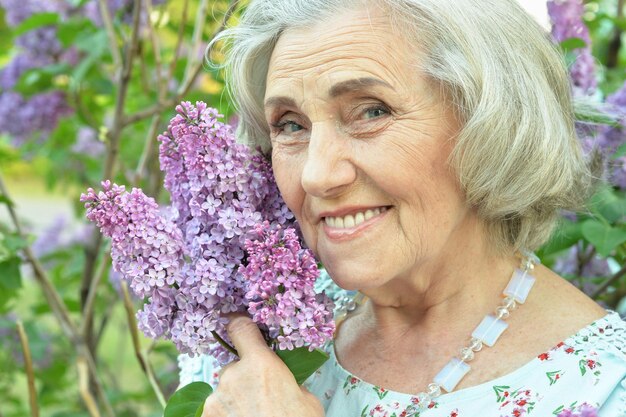 Happy senior beautiful woman with lilacs