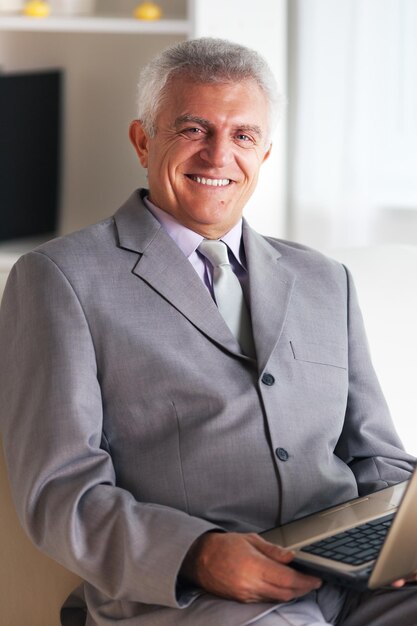 Happy Senior businessman working at home on laptop.