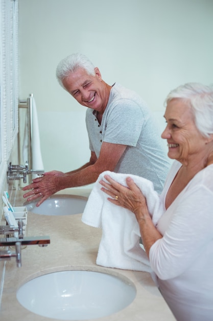 Happy senior couple cleaning hands in bathroom