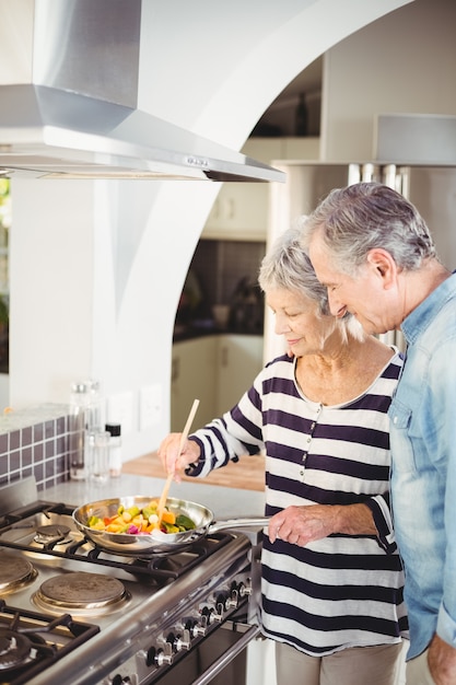 Foto coppie senior felici che cucinano alimento