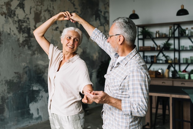 Happy senior couple dancing in the home