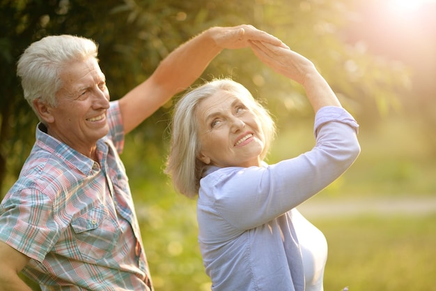 Happy senior couple dancing in summer park