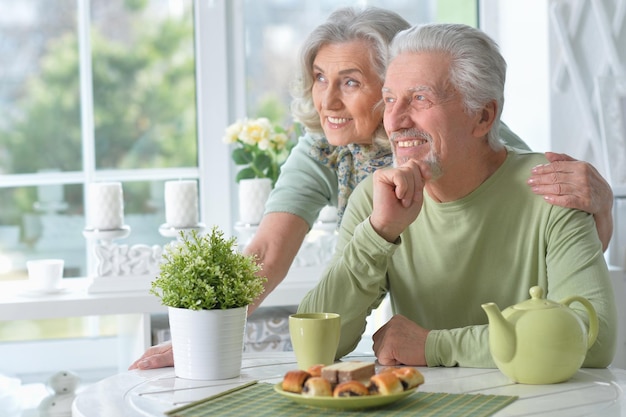 Счастливая пожилая пара пьет чай и позирует дома