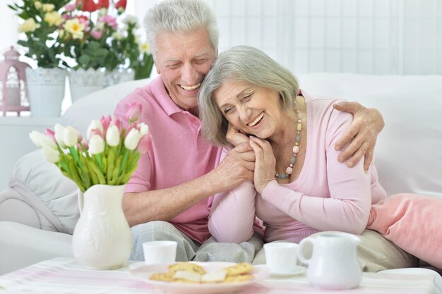 Happy senior couple  drinking tea with cookies