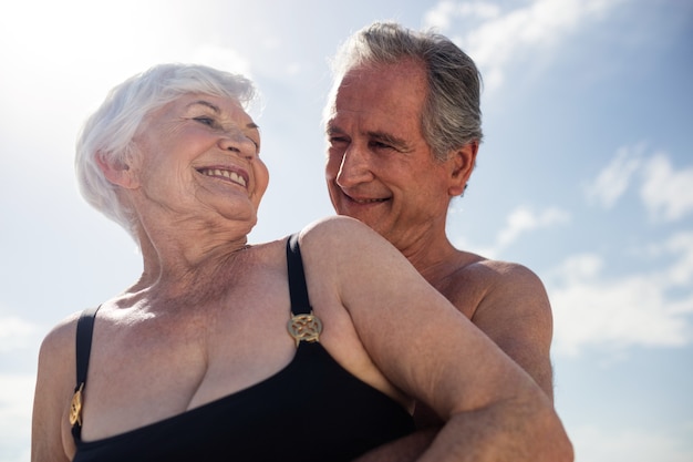 Felice coppia senior abbracciando sulla spiaggia