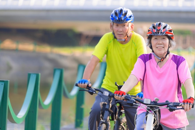 公園で自転車で運動する幸せなシニアカップル