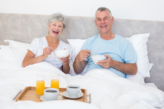 Happy senior couple having breakfast in bed