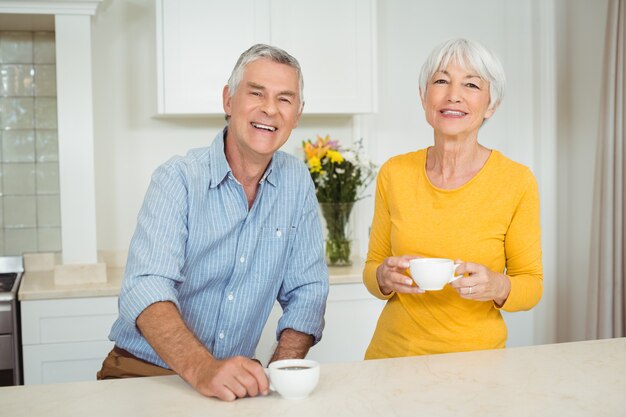 Happy senior couple having coffee in kitchen