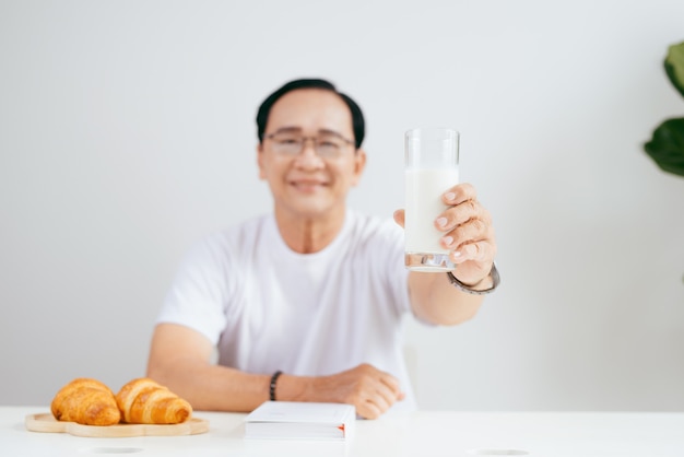 Happy senior couple having croissant breakfast at home and drinking milk.