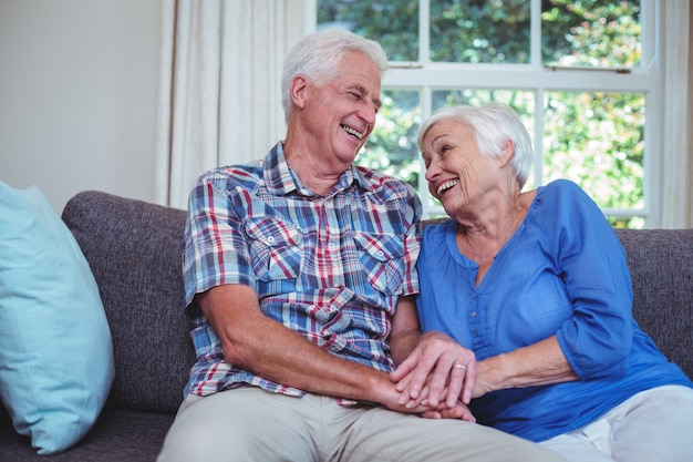 Happy senior couple holding hands at home