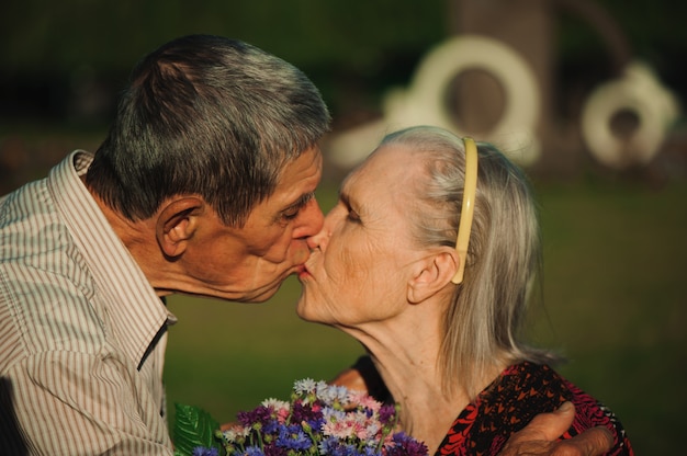 Foto le coppie senior felici nell'amore, parcheggiano all'aperto.