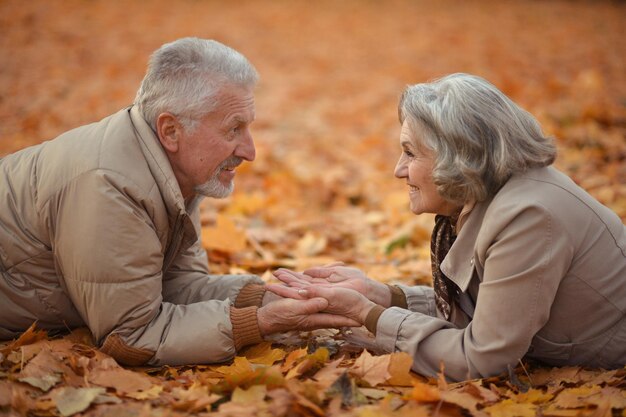 紅葉の上に横たわる幸せな年配のカップル