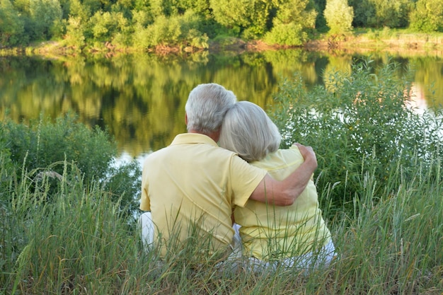 Happy senior couple near lake during sunset at summer