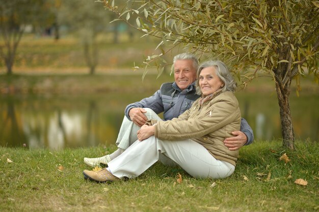 Счастливая пара старших у реки осенью, размытый фон