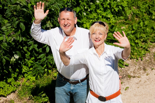 Photo happy senior couple outdoors waving hands