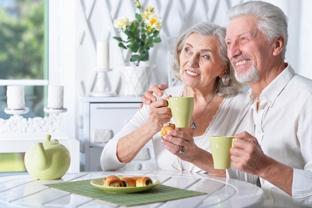 家でお茶を飲む幸せなシニアカップルの肖像画