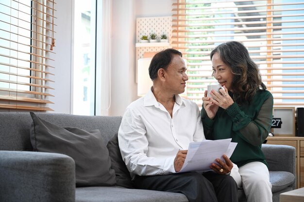 Happy senior couple relaxing on couch spending time together in cozy living room