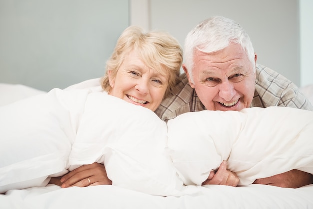 Happy senior couple resting on bed