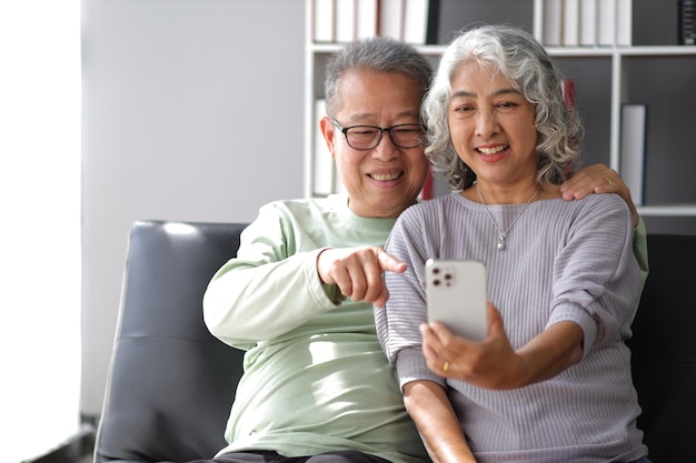 happy senior couple in retirement at home happy grandfather and grandmother talking with grandchildren from home by video call on smartphone