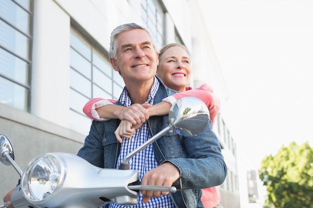 Happy senior couple riding a moped 