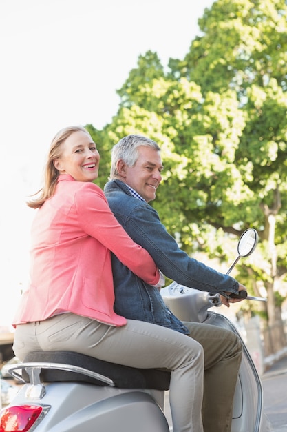 Happy senior couple riding a moped 