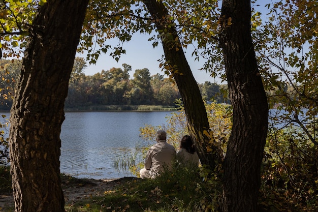 Happy senior couple sitting in near lake during sunset