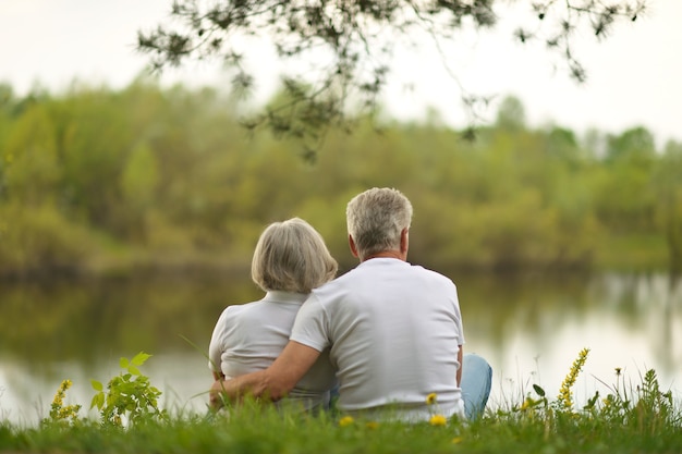 Happy senior couple sitting in summer near lake