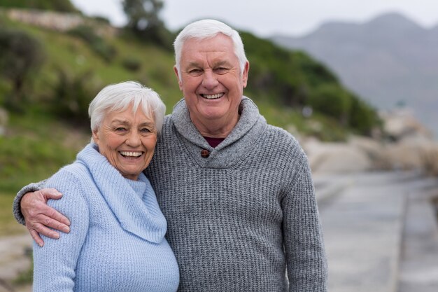 Счастливая пара старших, стоя вместе на пляже