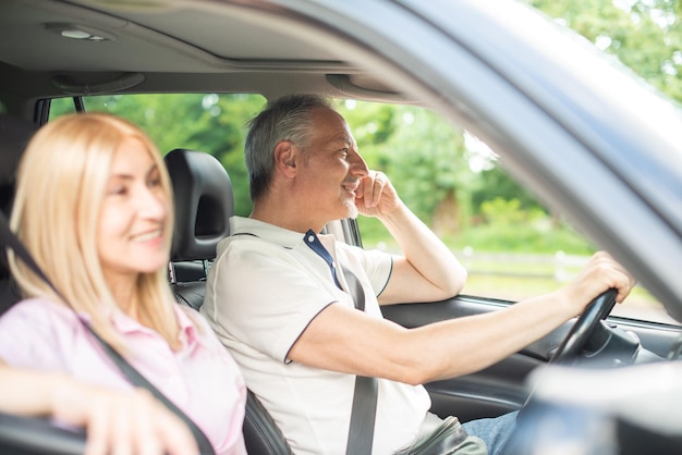 Happy senior couple traveling in their car