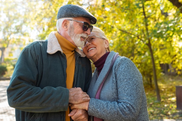 Photo happy senior couple walking in autumn park holding hands