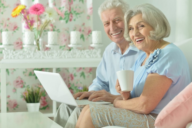 Счастливая пара старших с ноутбуком дома
