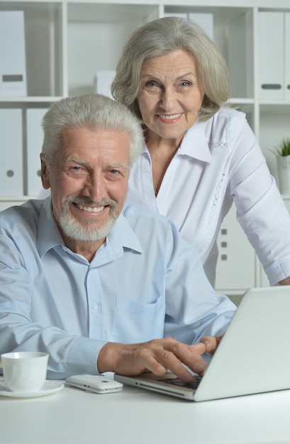 Happy senior couple with laptop  in office