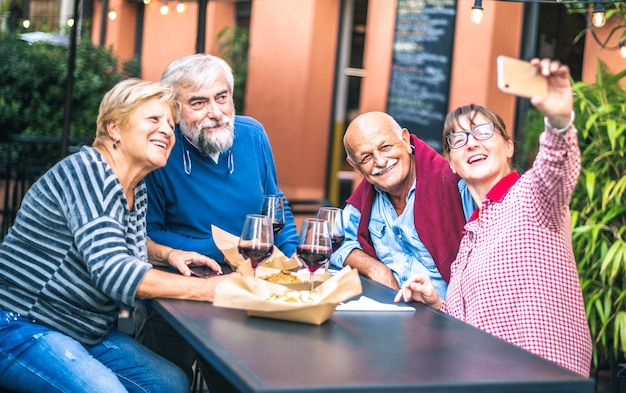 Photo happy senior friends taking selfie at restaurant