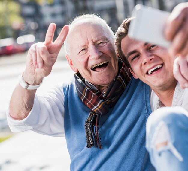 Photo happy senior man and adult grandson taking a selfie