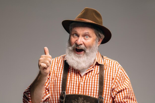 Happy senior man dressed in traditional Austrian or Bavarian costume gesturing