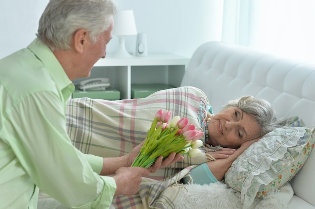 Happy senior man gives flowers to a woman