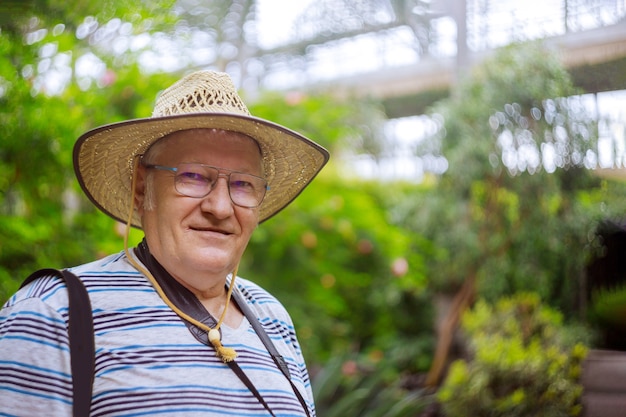 Happy senior man relaxing in park through the trees with soft focus