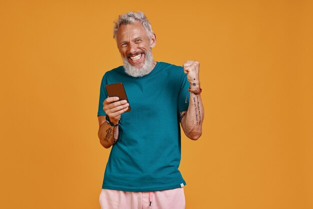 Happy senior man using smart phone and smiling 