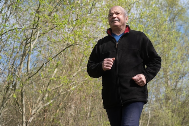 Happy senior man walking and relaxing in park