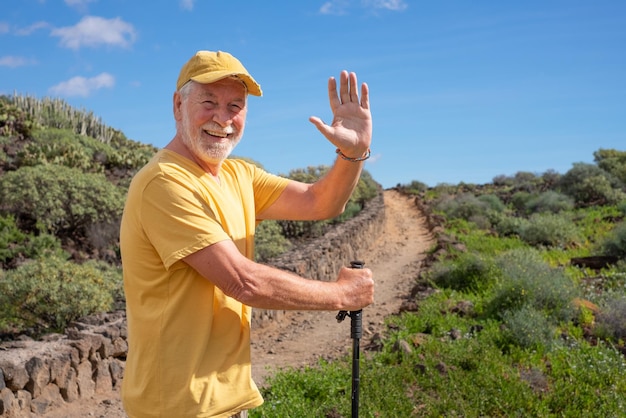Photo happy senior man walking in a sunny day on trail outdoors on mountain excursion relaxed caucasian man enjoying travel or retirement leading healthy lifestyle