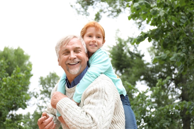 Счастливый старший мужчина с внучкой в парке