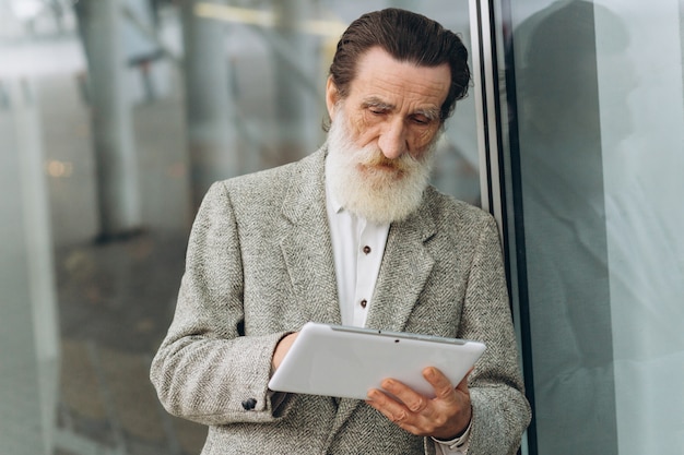 Happy senior man with the tablet on the office buildings