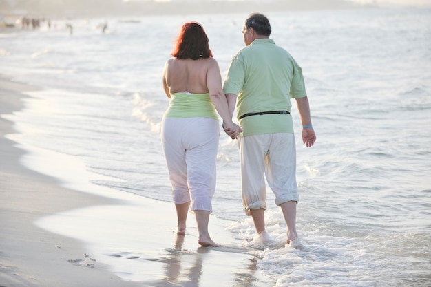 счастливая пожилая пара пожилых людей проводит романтическое время на пляже на закате