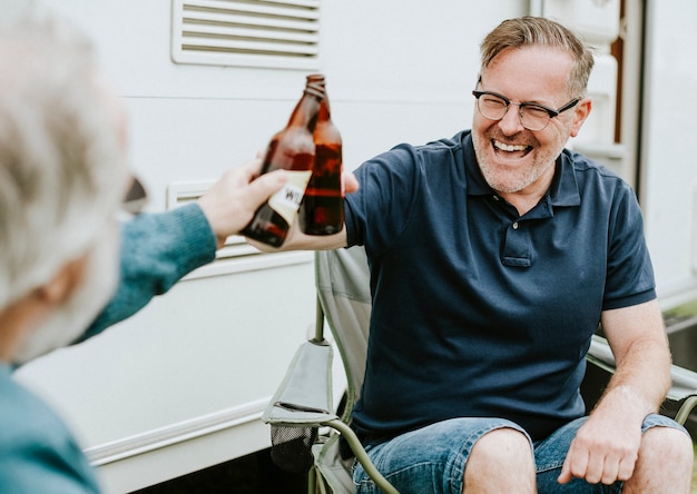 Счастливые пожилые люди звон бутылочного пива