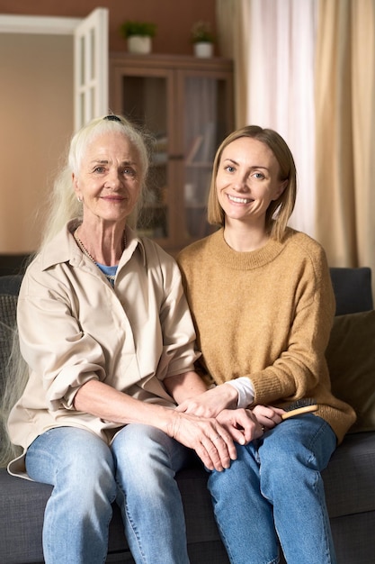 Happy senior mom sitting at home with her adult daughter