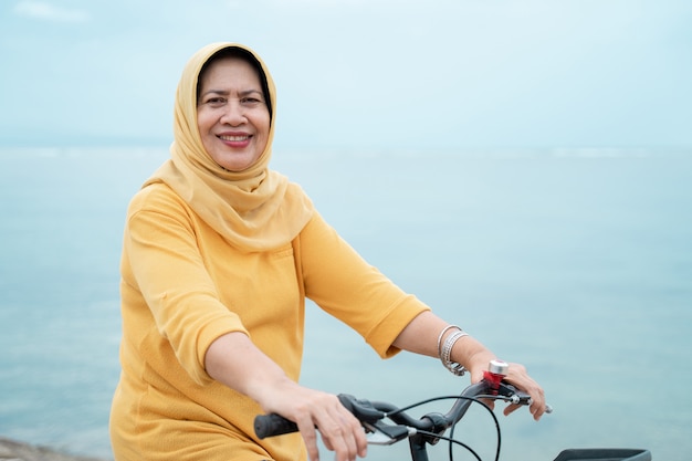 Happy senior muslim female riding a bicycle