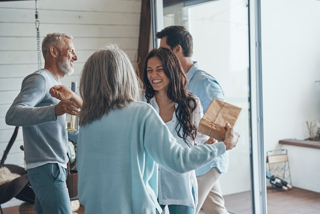 Happy senior parents meeting young couple inside the house